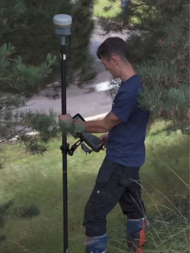 topógrafo midiendo con su GPS en una zona de árboles